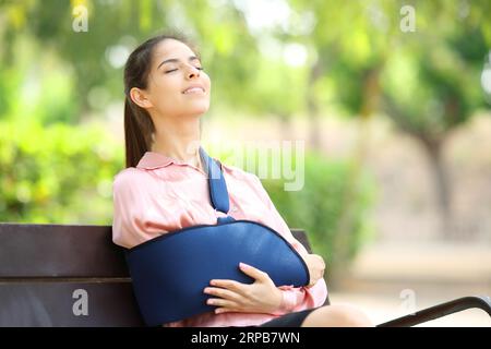 Heureuse femme handicapée respirant assise sur un banc dans un parc Banque D'Images