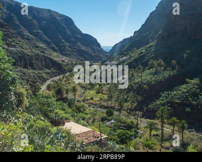 Vue sur le village El Cabezo dans la vallée verdoyante avec des palmiers, des maisons colorées traditionnelles. Début du sentier de randonnée à travers Barranco de Guarimiar gorge. La Banque D'Images