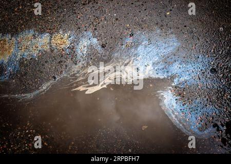 Fuite d'huile ou d'essence sous la voiture sur l'asphalte dans le stationnement. Banque D'Images