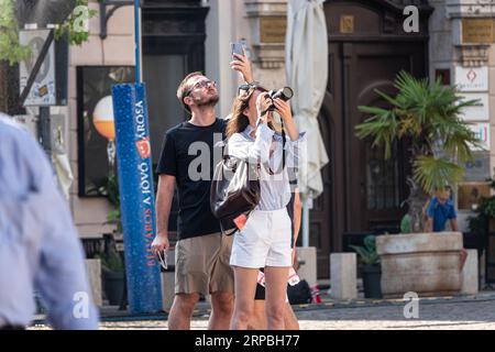 Touristes prenant des photos dans les rues d'une ville. Banque D'Images