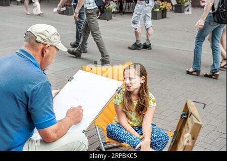 Moscou, Russie, 2015.07.09 Un artiste de rue dessine un croquis d'un portrait d'une fille sérieuse. Street artist dessine le portrait d'une fille dans la rue. Banque D'Images