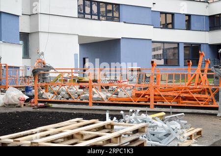 Grande façade de bâtiment en fer métallique support d'ascenseur pour soulever les travailleurs et une charge de matériaux de construction pendant la réparation de la façade extérieure et de l'aap Banque D'Images