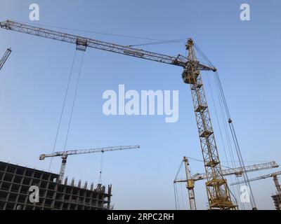 grue de construction sur un fond de ciel bleu. grue pour le déplacement de blocs de béton lourds pour la construction de maisons et de bâtiments de grande hauteur. Banque D'Images