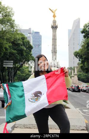 Femme adulte latine montre le drapeau du mexique fière de la culture et de la tradition de son pays, célèbre le patriotisme mexicain Banque D'Images