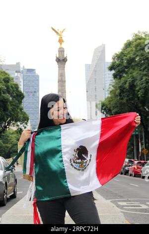 Femme adulte latine montre le drapeau du mexique fière de la culture et de la tradition de son pays, célèbre le patriotisme mexicain Banque D'Images