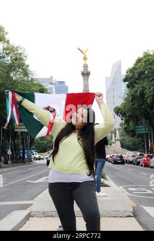 Femme adulte latine montre le drapeau du mexique fière de la culture et de la tradition de son pays, célèbre le patriotisme mexicain Banque D'Images