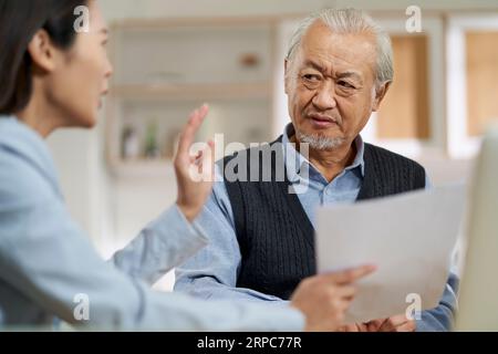 senior asian man appears to be confused by and suspicious at a sales person selling financial product Stock Photo
