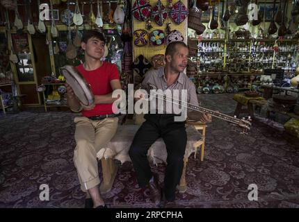 (190711) -- KASHGAR, 11 juillet 2019 -- le propriétaire d'une boutique d'artisanat en bois (L) et un membre du personnel jouent d'instruments de musique dans l'ancienne ville de Kashgar, dans la région autonome ouïgour du Xinjiang du nord-ouest de la Chine, le 6 juillet 2019. Au cours du premier semestre de 2019, l ' ancienne ville de Kashgar a accueilli plus de 310 000 000 touristes. CHINE-XINJIANG-KASHGAR ANCIENNE VILLE-TOURISME (CN) ZHAOXGE PUBLICATIONXNOTXINXCHN Banque D'Images