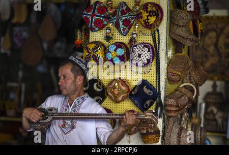 (190711) -- KASHGAR, 11 juillet 2019 -- un membre du personnel d'une boutique d'artisanat en bois joue d'un instrument de musique dans la ville antique de Kashgar, dans la région autonome ouïgoure du Xinjiang, au nord-ouest de la Chine, le 8 juillet 2019. Au cours du premier semestre de 2019, l ' ancienne ville de Kashgar a accueilli plus de 310 000 000 touristes. CHINE-XINJIANG-KASHGAR ANCIENNE VILLE-TOURISME (CN) ZHAOXGE PUBLICATIONXNOTXINXCHN Banque D'Images