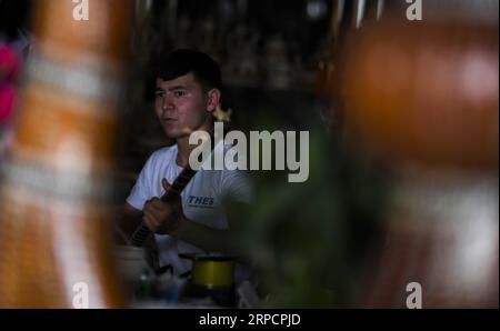 (190711) -- KASHGAR, 11 juillet 2019 -- le propriétaire d'une boutique d'artisanat en bois joue d'un instrument de musique dans l'ancienne ville de Kashgar, dans la région autonome ouïgoure du Xinjiang, au nord-ouest de la Chine, le 8 juillet 2019. Au cours du premier semestre de 2019, l ' ancienne ville de Kashgar a accueilli plus de 310 000 000 touristes. CHINE-XINJIANG-KASHGAR ANCIENNE VILLE-TOURISME (CN) ZHAOXGE PUBLICATIONXNOTXINXCHN Banque D'Images