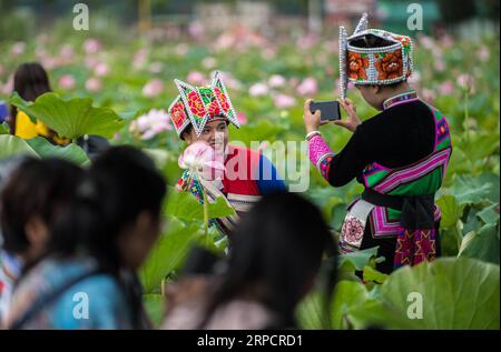 (190712) -- QIUBEI, le 12 juillet 2019 -- un visiteur de l'ethnie Zhuang pose pour une photo avec une fleur de lotus dans le parc national des zones humides de Puzhehehei dans le comté de Qiubei, dans le sud-ouest de la Chine, province du Yunnan, le 11 juillet 2019.) CHINA-YUNNAN-QIUBEI-PUZHEHEHEI PARC NATIONAL DES ZONES HUMIDES (CN) JIANGXWENYAO PUBLICATIONXNOTXINXCHN Banque D'Images