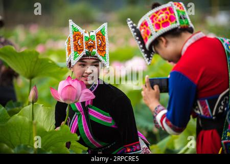 (190712) -- QIUBEI, le 12 juillet 2019 -- un visiteur de l'ethnie Zhuang pose pour une photo avec une fleur de lotus dans le parc national des zones humides de Puzhehehei dans le comté de Qiubei, dans le sud-ouest de la Chine, province du Yunnan, le 11 juillet 2019.) CHINA-YUNNAN-QIUBEI-PUZHEHEHEI PARC NATIONAL DES ZONES HUMIDES (CN) JIANGXWENYAO PUBLICATIONXNOTXINXCHN Banque D'Images