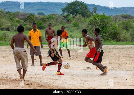 BEKOPAKA, MADAGASCAR - 6 NOVEMBRE 2022 : un groupe de jeunes hommes jouent au football sur un terrain de terre à Bekopaka, un village rural de l'ouest de Madagascar. Le jeu Banque D'Images