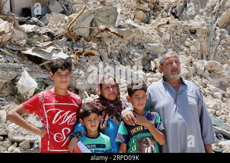 (190717) -- MOSSOUL, 17 juillet 2019 -- Laith Najim (1e R) et les membres de sa famille se tiennent devant la maison détruite de leur voisin dans la vieille ville de Mossoul, Irak, le 14 juillet 2019. La guerre pour libérer Mossoul de l Irak du groupe militant État islamique (EI) remporte la victoire depuis deux ans, mais ses graves impacts pèsent encore lourdement sur les habitants de la ville. Une campagne de collecte de fonds populaire a été lancée dans les médias sociaux chinois avec une solidarité écrasante, visant à apporter de l'espoir aux familles déchirées par la guerre à Mossoul en Irak. POUR ALLER AVEC la caractéristique : les dons de la base chinoise apportent de l'espoir aux fami déchirés par la guerre Banque D'Images