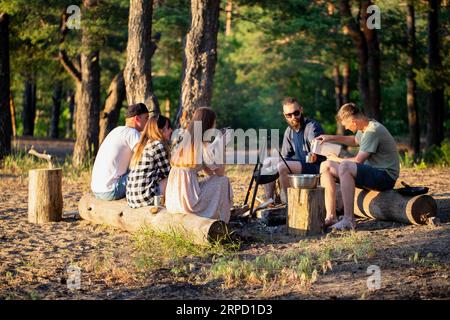 Une compagnie d'amis de filles et de gars se reposer en été dans un endroit pittoresque dans la forêt sur les rives de la rivière dans le contexte o Banque D'Images