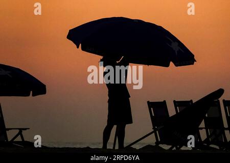 Île de Palms, États-Unis. 04 septembre 2023. Un ouvrier positionne des parasols et des chaises découpées par la lumière du jour pour les foules de plage à la fin officieuse de l'été marqué par la fête du travail, le 4 septembre 2023 à Isle of Palms, Caroline du Sud. Crédit : Richard Ellis/Richard Ellis/Alamy Live News Banque D'Images