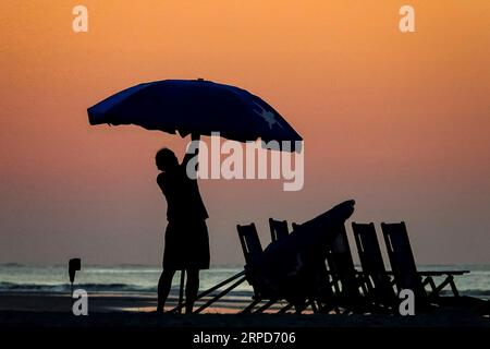 Île de Palms, États-Unis. 04 septembre 2023. Un ouvrier positionne des parasols et des chaises découpées par la lumière du jour pour les foules de plage à la fin officieuse de l'été marqué par la fête du travail, le 4 septembre 2023 à Isle of Palms, Caroline du Sud. Crédit : Richard Ellis/Richard Ellis/Alamy Live News Banque D'Images