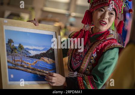 (190807) -- SHIPING, 7 août 2019 -- Zhang Hua expose son patchwork de plumes aux touristes dans le comté de Shiping, préfecture autonome de Hani-Yi de Honghe, province du Yunnan au sud-ouest de la Chine, 7 août 2019. Né dans le canton de Longpeng dans le comté de Shiping, Zhang Hua, de l'ethnie Yi, s'intéresse à la broderie Yi dès son plus jeune âge et a commencé à apprendre la fabrication de patchwork de plumes depuis 2009. En 2016, Zhang Hua a fondé un studio pour aider les femmes locales à apprendre la broderie et l'art des plumes gratuitement. Puis, avec le soutien du gouvernement local, elle a organisé une coopérative spécialisée dans l’art des plumes pour booster loca Banque D'Images