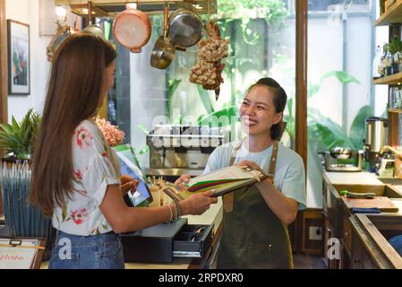 Jeune serveuse vietnamienne travaillant avec la machine de check out et les clients dans le café Banque D'Images