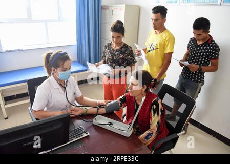 (190816) -- KASHGAR, 16 août 2019 -- les résidents reçoivent un examen médical gratuit dans le canton de Tongan du comté de Zepu, Kashgar, région autonome ouïgour du Xinjiang du nord-ouest de la Chine, 16 août 2019. Une fois vivant dans le canton de Kosirap, dans la région éloignée des montagnes Kunlun, 1 194 ménages ont été relocalisés dans le canton de Tongan, à 94 kilomètres de l’endroit d’origine, en août 2018. Grâce à une série de mesures favorables prises, la ville relocalisée a pu accéder à l'alimentation électrique, à de meilleures conditions routières et à des soins de santé. En outre, les autorités locales augmentent les revenus des villageois en attirant les investissements et en se développant Banque D'Images