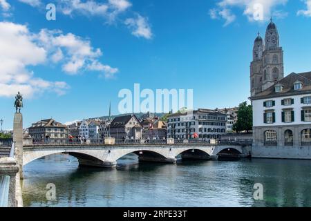 Zurich, Suisse-27 mai 2023 ; Munsterbrucke (pont) au-dessus de la rivière Limmat à Altstadt Zurich avec l'église Grossmünster contre un bleu blanc nuageux Banque D'Images