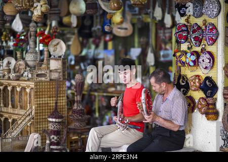 (190817) -- URUMQI, 17 août 2019 -- Yumaerjan Usaan (à gauche) et son père Yusaanjan Yusuyin jouent un duo dutar-tabour dans leur atelier d'artisanat en bois à Kashgar, dans la région autonome ouïgour du Xinjiang, au nord-ouest de la Chine, le 6 juillet 2019.) Xinhua titres : Xinjiang : région extrême ouest, cœur de la route de la soie ZhaoxGe PUBLICATIONxNOTxINxCHN Banque D'Images