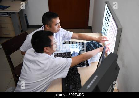 (190818) -- CHANGSHA, 18 août 2019 -- le docteur Xiao Yangbao (UP) regarde des radiographies avec un radiologue au centre d'endoscopie de l'hôpital thoracique du Hunan à Changsha, capitale de la province du Hunan en Chine centrale, 15 août 2019. Xiao Yangbao, un médecin de 39 ans du centre d’endoscopie de l’hôpital thoracique du Hunan, travaille sur la prévention et le traitement de la tuberculose depuis près de 8 ans. En tant que médecin effectuant des opérations d'endoscopie, Xiao est confronté à des risques d'exposition plus élevés à la tuberculose et à des exigences opératoires plus élevées en termes de précision et de concentration. Xiao se sent toujours gratifié à chaque fois que son patient Banque D'Images