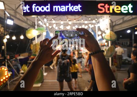 (190818) -- BANGKOK, 18 août 2019 -- Un touriste prend des photos au marché nocturne asiatique, à Bangkok, Thaïlande, le 10 août 2019.) THAÏLANDE-BANGKOK-MARCHÉ NOCTURNE ZhangxKeren PUBLICATIONxNOTxINxCHN Banque D'Images