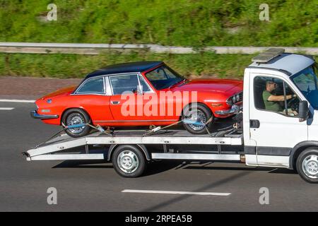 Voiture Triumph Stage vintage sur remorque fourgonnette Iveco ; voyageant à grande vitesse sur l'autoroute M6 dans le Grand Manchester, Royaume-Uni Banque D'Images