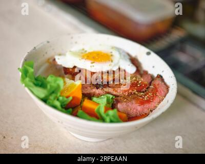 Steak de bœuf avec un œuf au plat, riz et légumes. Banque D'Images