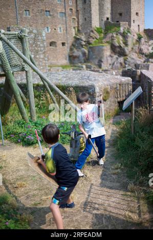 Deux jeunes garçons caucasiens prétendent se battre avec des épées et des boucliers en bois lors d'une visite d'un château historique Banque D'Images