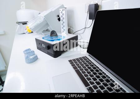 Ordinateur portable et dispositif pour laver une empreinte dentaire 3D dans une solution de nettoyage et traiter le moule à l'aide de la lumière UV. Banque D'Images