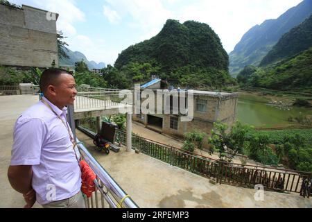 (190901) -- LINGYUN, 1 septembre 2019 -- Lao Ketuan regarde le village depuis son domicile dans le village de Haokun, dans le comté de Lingyun, dans la région autonome de Guangxi Zhuang, dans le sud de la Chine, le 30 août 2019. Lao Ketuan, 40 ans, vit dans le village montagneux de Haokun, un endroit où les transports sont extrêmement médiocres et où les ressources foncières sont rares, ce qui a sérieusement entravé le développement local et a plongé les gens dans la pauvreté. La famille AJO fait partie des ménages pauvres qui vivent ici. En 2016, Lao n’avait cependant jamais rêvé que sa famille puisse sortir de la pauvreté grâce au travail des autorités locales sur la lutte contre la pauvreté Banque D'Images