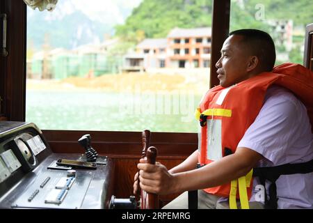 (190901) -- LINGYUN, 1 septembre 2019 -- Lao Ketuan conduit son bateau touristique au point pittoresque du lac Haokun dans le comté de Lingyun, dans la région autonome de Guangxi Zhuang, dans le sud de la Chine, 30 août 2019. Lao Ketuan, 40 ans, vit dans le village montagneux de Haokun, un endroit où les transports sont extrêmement médiocres et où les ressources foncières sont rares, ce qui a sérieusement entravé le développement local et a plongé les gens dans la pauvreté. La famille AJO fait partie des ménages pauvres qui vivent ici. En 2016, Lao n’avait cependant jamais rêvé que sa famille puisse sortir de la pauvreté grâce au travail des autorités locales sur la pauvreté allev Banque D'Images