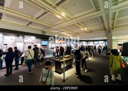 Vue intérieure, les gens regardent des expositions dans la salle de la table des médias dédiée aux dangers de la guerre nucléaire dans le musée de la paix d'Hiroshima. Banque D'Images