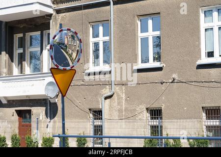 Près de la maison au carrefour il y a un signe - céder la place et un miroir de visualisation pend. Panneaux de signalisation. Banque D'Images