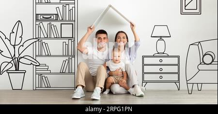 Couple avec Baby Holding Roof près du mur avec illustrations de la maison Banque D'Images