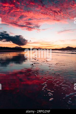 Vue de la belle heure dorée sur la Famara.' Plage à Lanzarote - Îles Canaries. Photo verticale du coucher de soleil sur la plage avec reflet de l'océan et Banque D'Images