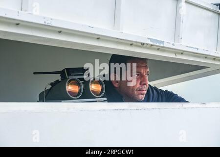 Un belvédère employé par des compagnies d'observation des baleines regarde à travers des jumelles alors qu'il regarde l'océan Atlantique pour des observations de baleines près d'Agua de Pau, île de Sao Miguel, Açores, Portugal. Les postes d'observation de la chasse à la baleine étaient autrefois utilisés par l'industrie baleinière pour chasser les baleines et font maintenant partie de l'éco-industrie d'observation des baleines, qui a connu un succès et est durable. Banque D'Images