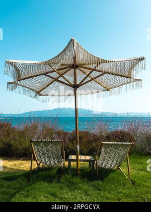 Deux chaises longues sur l'herbe avec parasol, chaises longues vides avec le concept d'application environnementale Seaascape. Photo de haute qualité Banque D'Images