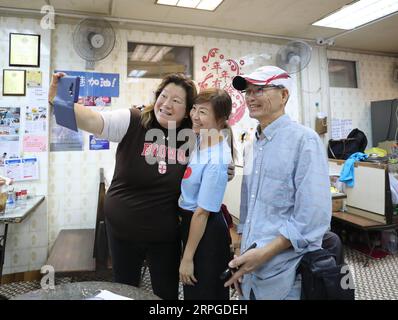 191012 -- HONG KONG, le 12 octobre 2019 -- Kate Lee C pose pour un selfie avec des clients dans son restaurant de thé à Kowloon, Hong Kong du sud de la Chine, le 10 octobre 2019. Niché dans le labyrinthe du marché de fruits de mer du paisible village de pêcheurs de Lei Yue Mun à Hong Kong, un petit restaurant de thé douillet est devenu de manière inattendue un phare de courage pour les gens ordinaires de Hong Kong qui cherchent la paix dans le chaos récent. Après avoir posté des photos soutenant la police de Hong Kong contre certains manifestants radicaux à la fin du mois de juin, Kate Lee, la propriétaire du restaurant de thé, a constaté que sa conscience avait un lourd tribut sur sa famille Banque D'Images