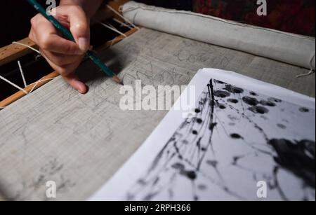 191028 -- NANCHANG, 28 octobre 2019 -- Zhang Xiaohong dessine le brouillon de broderie dans son atelier de Xinyu City, province du Jiangxi dans l'est de la Chine, le 23 octobre 2019. Datant de la dynastie des Song du Nord 960-1127, Xiabu, ou lin d'herbe, est une sorte de tissu fabriqué à partir de ramie. Zhang Xiaohong, 61 ans, est un héritier représentant national de la broderie Xiabu. En 2002, elle crée un atelier de broderie dans sa ville natale de Xinyu après avoir étudié à Tianjin et Suzhou. Au fil des ans, Zhang a mis à jour la qualité du tissu et a également créé six façons de points. En 2014, elle est reconnue comme la nati Banque D'Images