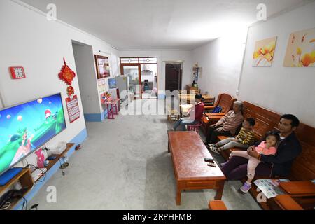 191107 -- LUOCHENG, 7 novembre 2019 -- Wu Caizhong et sa famille regardent la télévision dans leur nouvelle maison du comté de luocheng, dans la région autonome de Guangxi Zhuang, dans le sud de la Chine, le 6 novembre 2019. Wu Caizhong est une ethnie Mulao âgée de 36 ans. Sa famille, avec d'autres Mulao, vivait à Xiayantun du village de Mianhua, un village en proie à un développement inadéquat en raison de la désertification rocheuse karstique et des mauvaises conditions de circulation. En juin 2018, la famille Wu et d autres villageois ont été relogés dans un nouveau quartier résidentiel pour les Mulao à luocheng. Ce quartier résidentiel, avec plusieurs suppor Banque D'Images