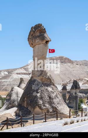 Une grande cheminée de fée dans le musée en plein air de Göreme en Cappadoce, Anatolie Turquie, avec un drapeau turc agitant dans le vent, vertical Banque D'Images