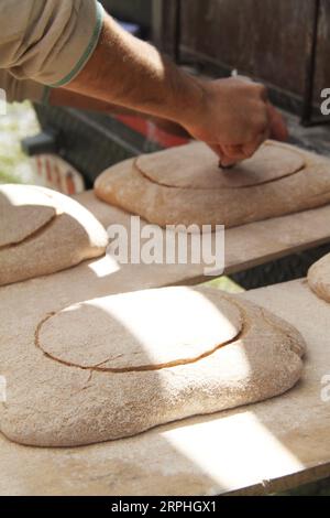 Baker découpe un motif dans la pâte avec un outil de rainurage Banque D'Images