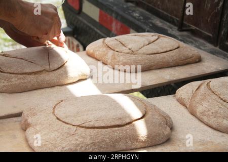 Baker découpe un motif dans la pâte avec un outil de rainurage Banque D'Images