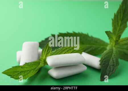 Savoureux chewing-gums blancs et feuilles de menthe sur fond vert, gros plan Banque D'Images