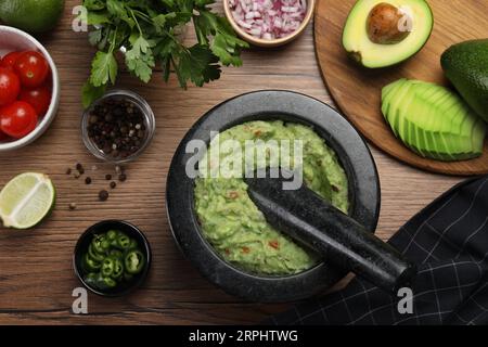 Délicieux guacamole dans le mortier et les ingrédients sur la table en bois, pose à plat Banque D'Images