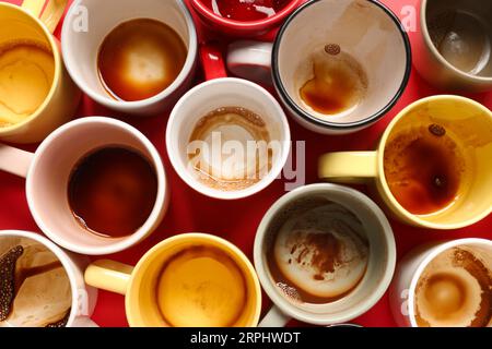 Beaucoup de tasses sales après avoir bu du café sur la table rouge, plat Banque D'Images