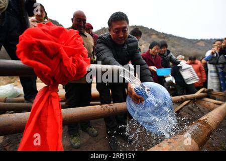 191122 -- COMTÉ DE YICHENG, 22 novembre 2019 -- les villageois se tiennent dans les lignes pour recueillir de l'eau après qu'un puits en eau profonde a commencé à pomper de l'eau souterraine dans le village de Nanling du comté de Yicheng, le 20 novembre 2019. Lorsque l'interrupteur a été tiré, l'eau a jailli de 403 mètres plus bas. Le tout premier puits en eau profonde de Nanling Village a été mis en service un matin tôt d hiver. Dans le passé, le village, qui s’étendait à travers les ravins des montagnes Zhongtiao dans le nord de la Chine, dépendait uniquement des fosses à boue pour stocker sa précieuse eau potable depuis des siècles. Hantées par la peur de la sécheresse, des générations avaient rêvé Banque D'Images